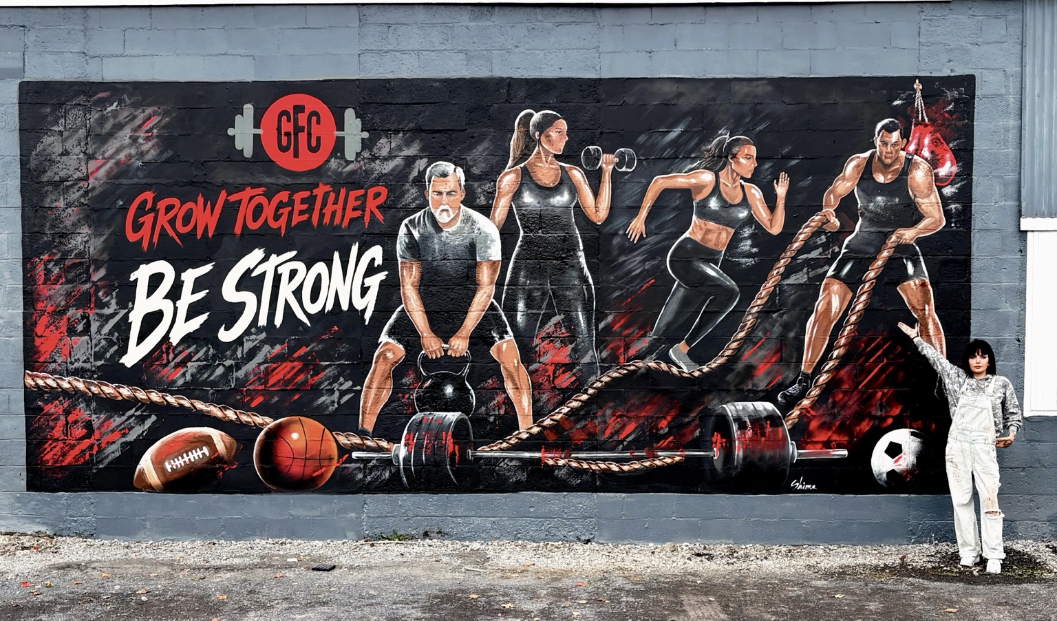 Shima standing beside the completed Grow Together mural